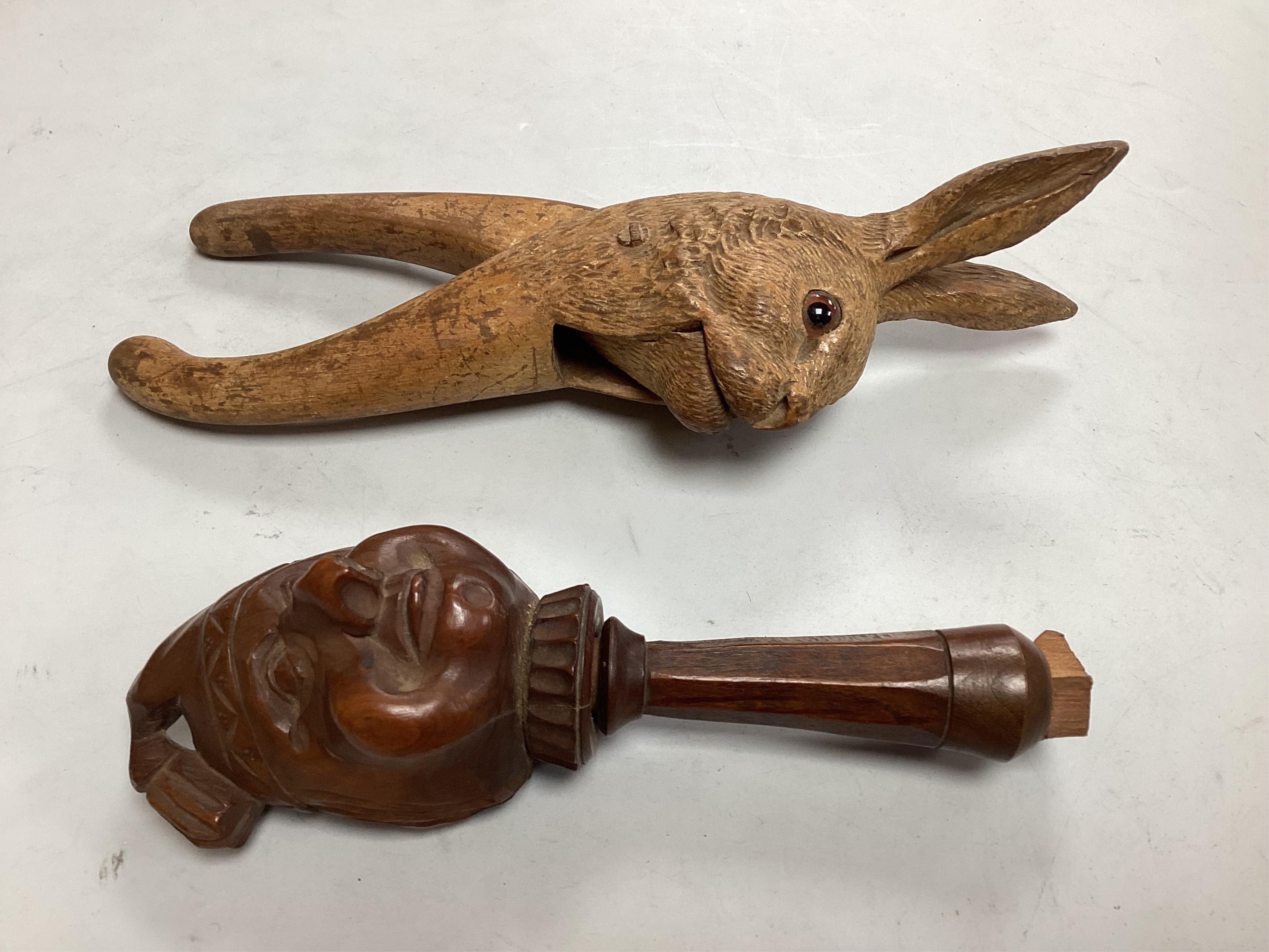 A pair of late 19th century Black Forest nutcrackers carvdd as a hare with glass eyes (loss) signed Champlex and a screw action novelty nutcracker carved with the head of a smiling man- 16.5cm high